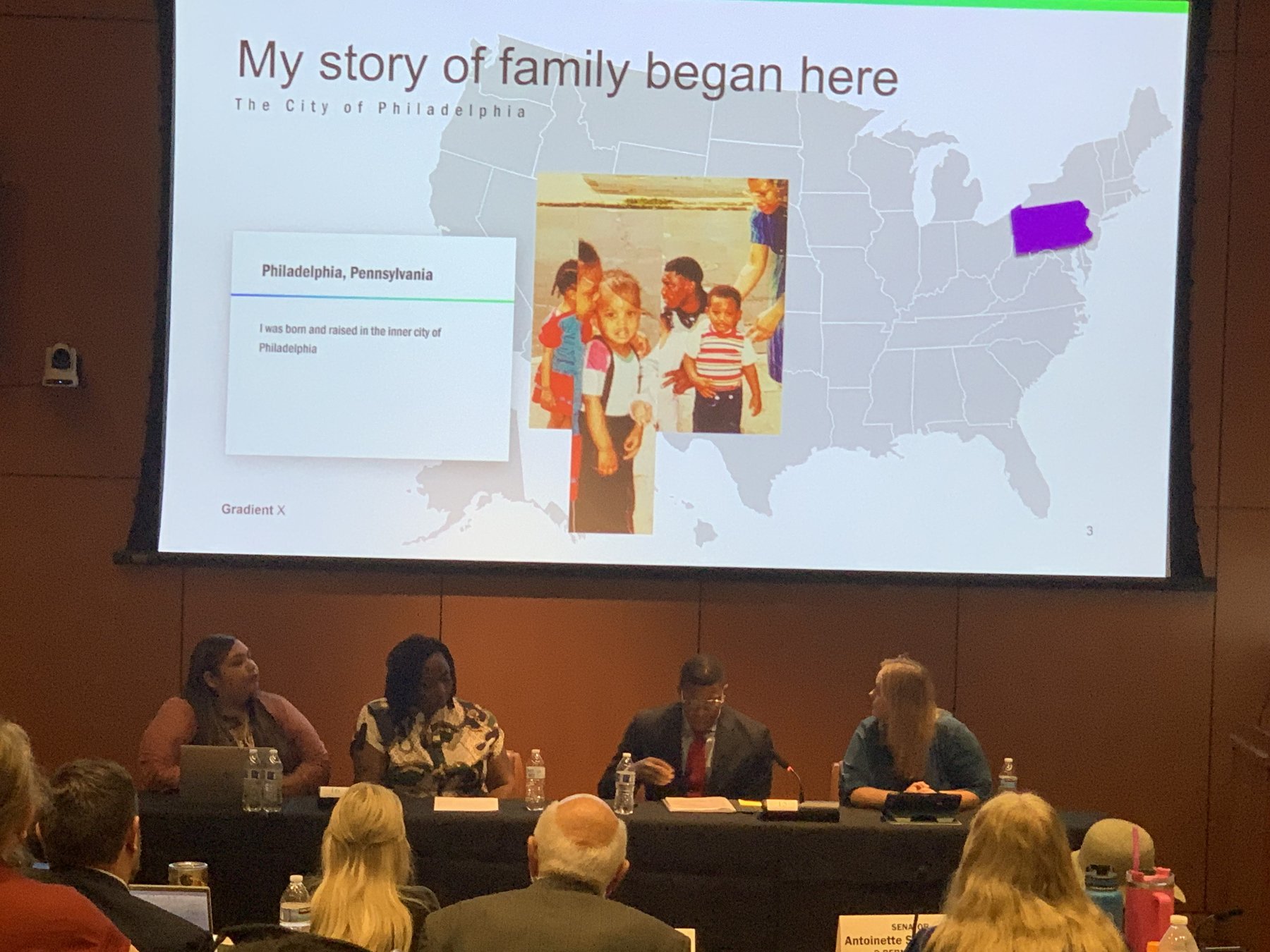 Takkeem Morgan on a New Mexico legislative panel, with a slide reading My story of family began here — The City of Philadelphia, projected behind the dais