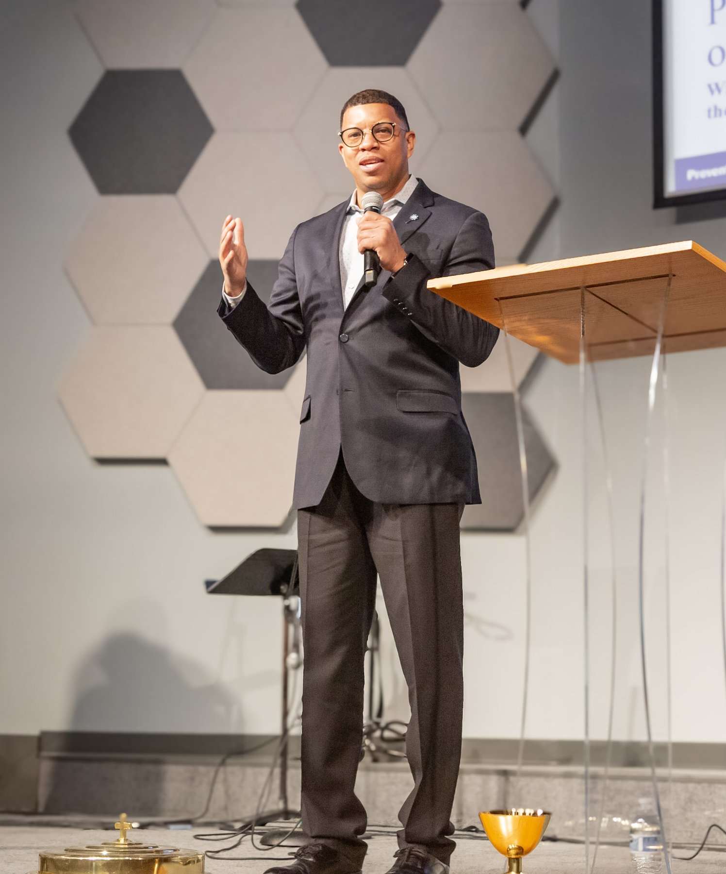 Wide stage shot of Takkeem Morgan holding a microphone during the Pinwheels of Possibility keynote